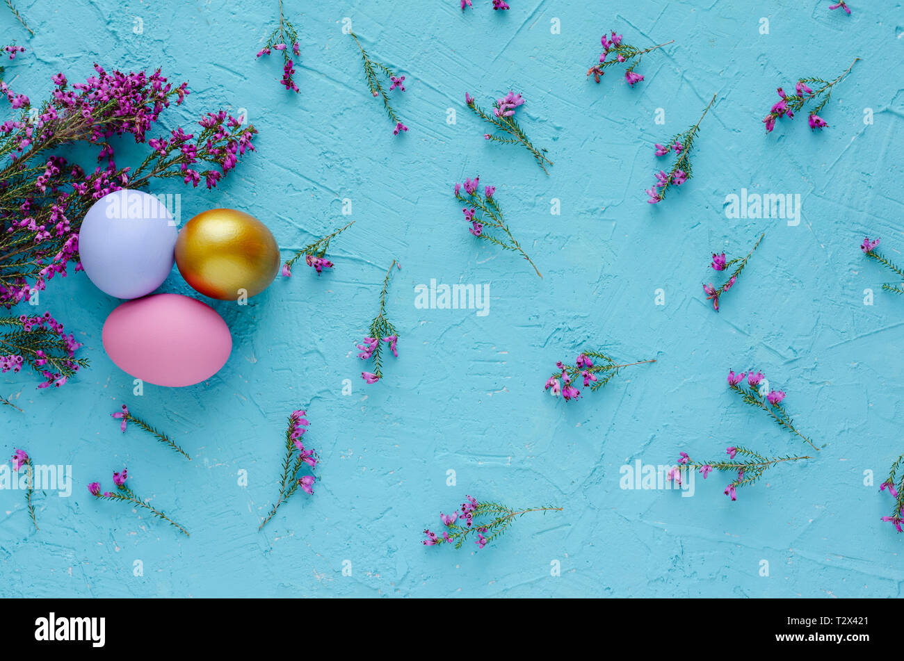 Three Easter eggs with heather flowers on blue background. Flat lay. Top view. Stock Photo