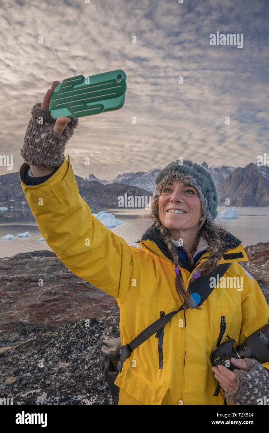 Woman taking a selfie with a cell phone, Scoresbysund, Greenland Stock Photo