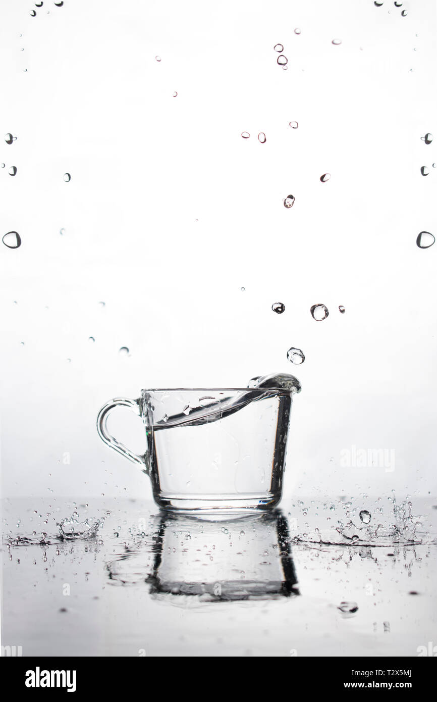 Splash of water from a glass on a white background. Reflection and