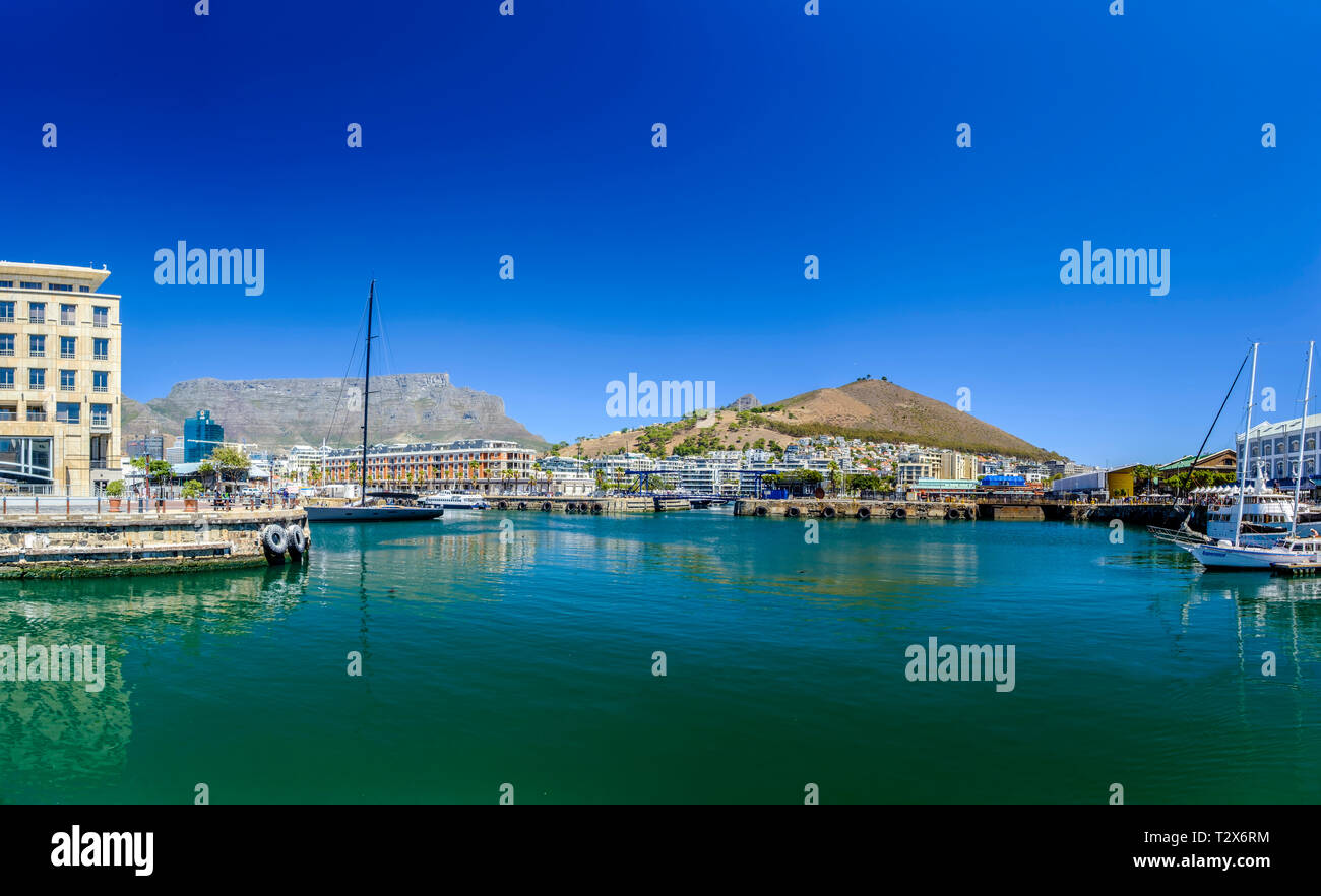 CAPE TOWN, SOUTH AFRICA – 20 MARCH 2018: Beautiful blue sky and water of harbor area Cape Town V&A Waterfront with backdrop of stunning Table Mountain Stock Photo