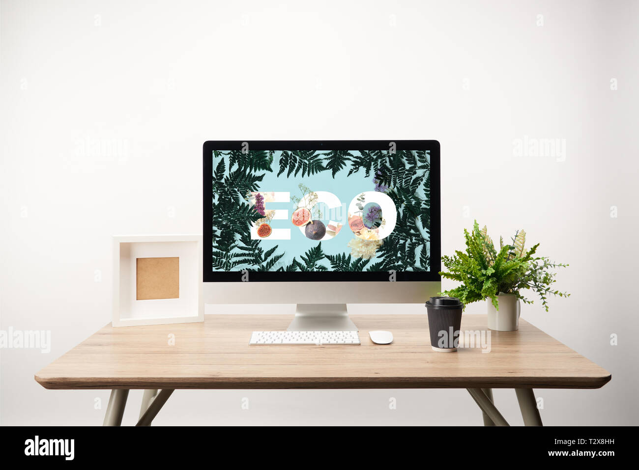 computer with green leaves and eco lettering on monitor on wooden desk ...