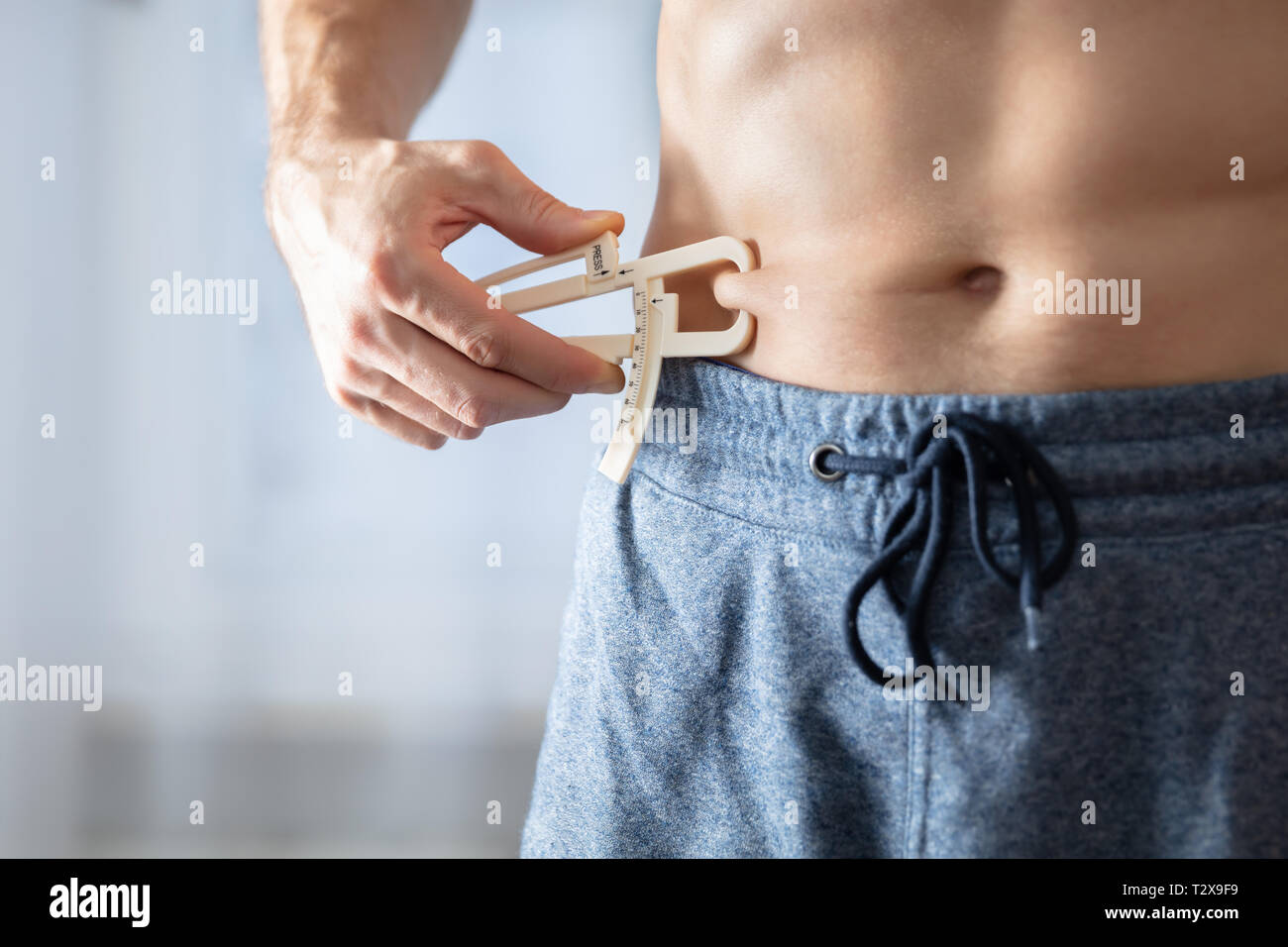 Close-up Of A Athlete Person Measuring His Body Fat With Caliper In The Gym Stock Photo