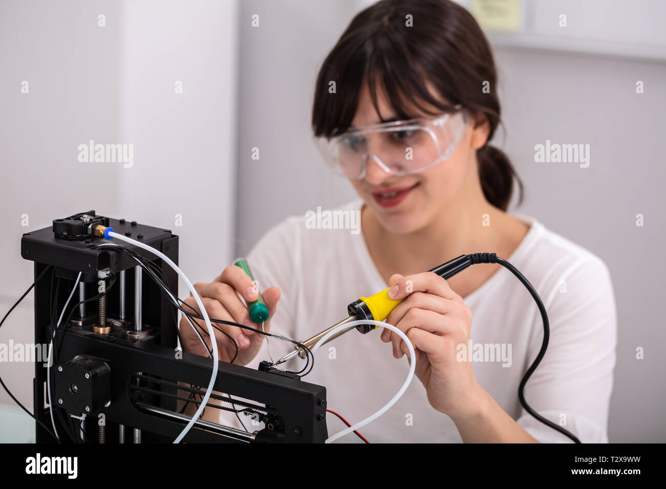 Young Female Technician Wearing Safety Eyeglasses Using Soldering Iron