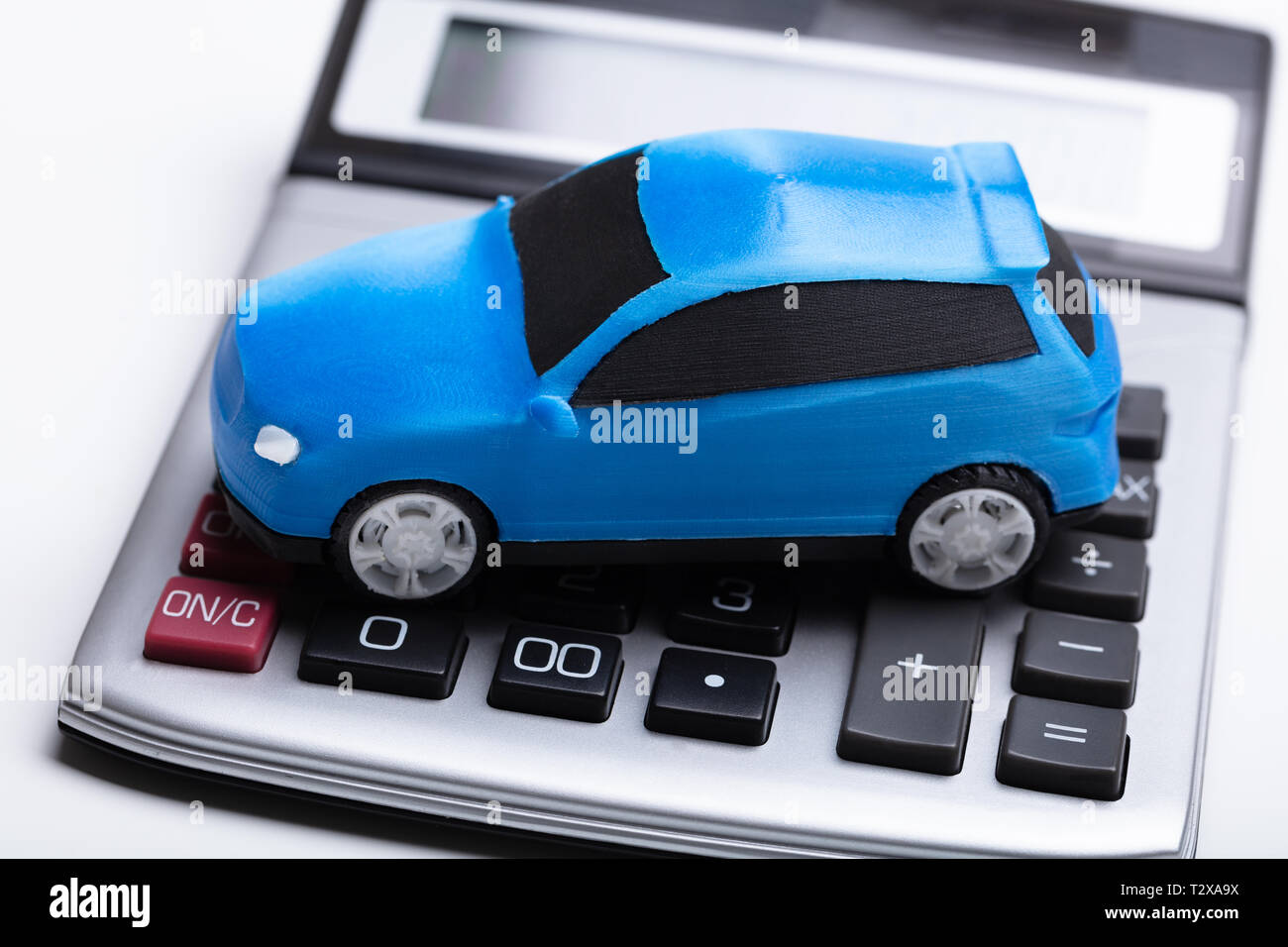 Close-up Of Blue Car And Calculator Against White Background Stock Photo