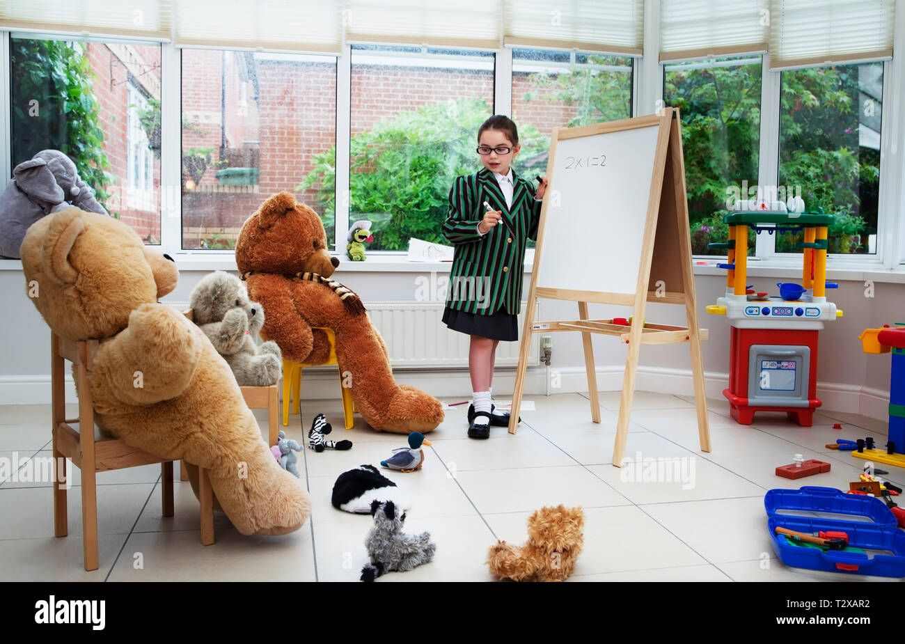 Caucasian girl pretending to teach her teddy bears Stock Photo
