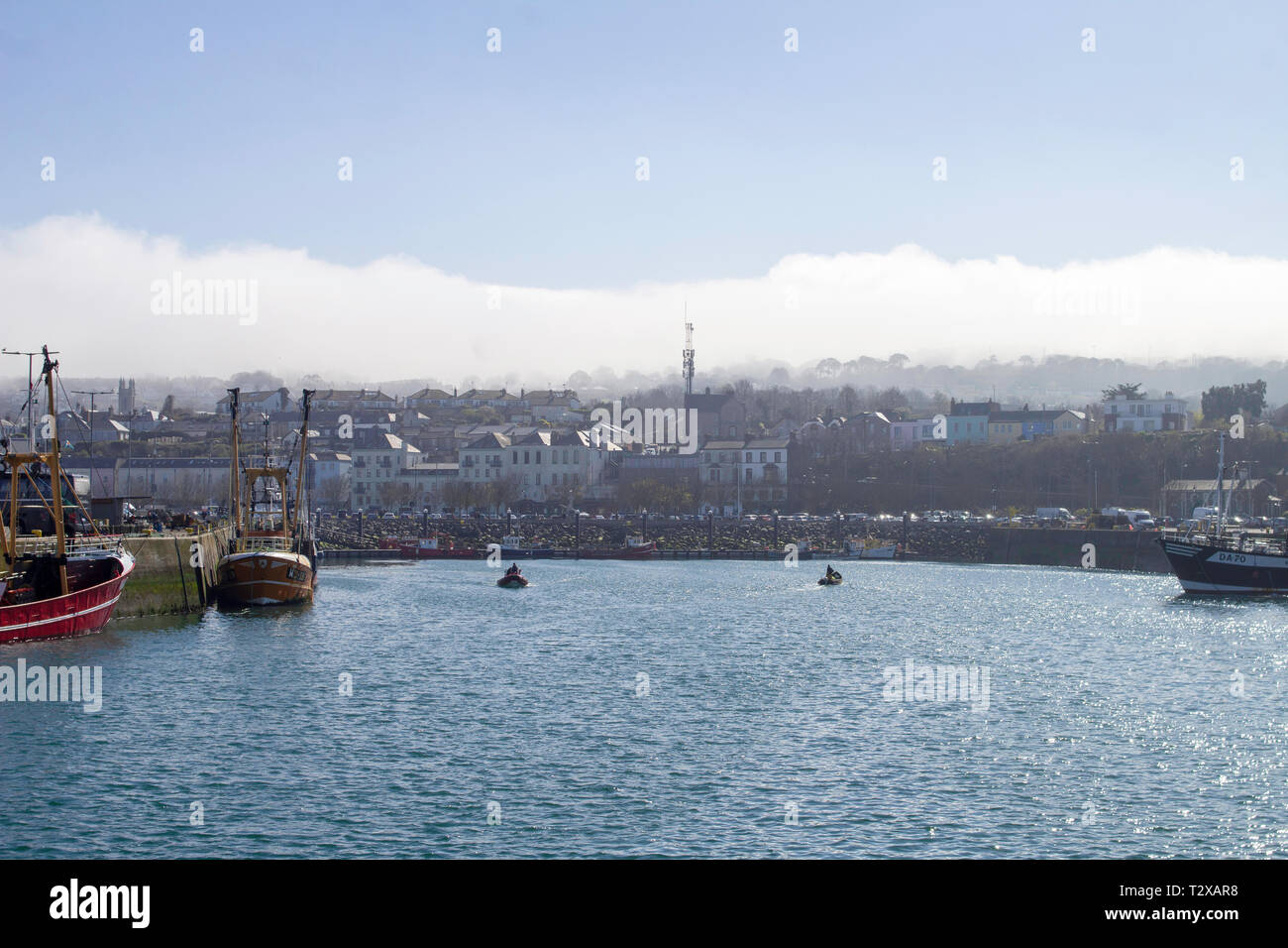 Howth Harbour in Dublin, Ireland with fishing  trawlers tied up and clouds rolling in over Howth Head,. Stock Photo