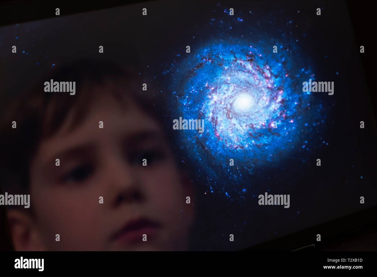 Reflection of a young boy looking at a galaxy on a tablet computer Stock Photo