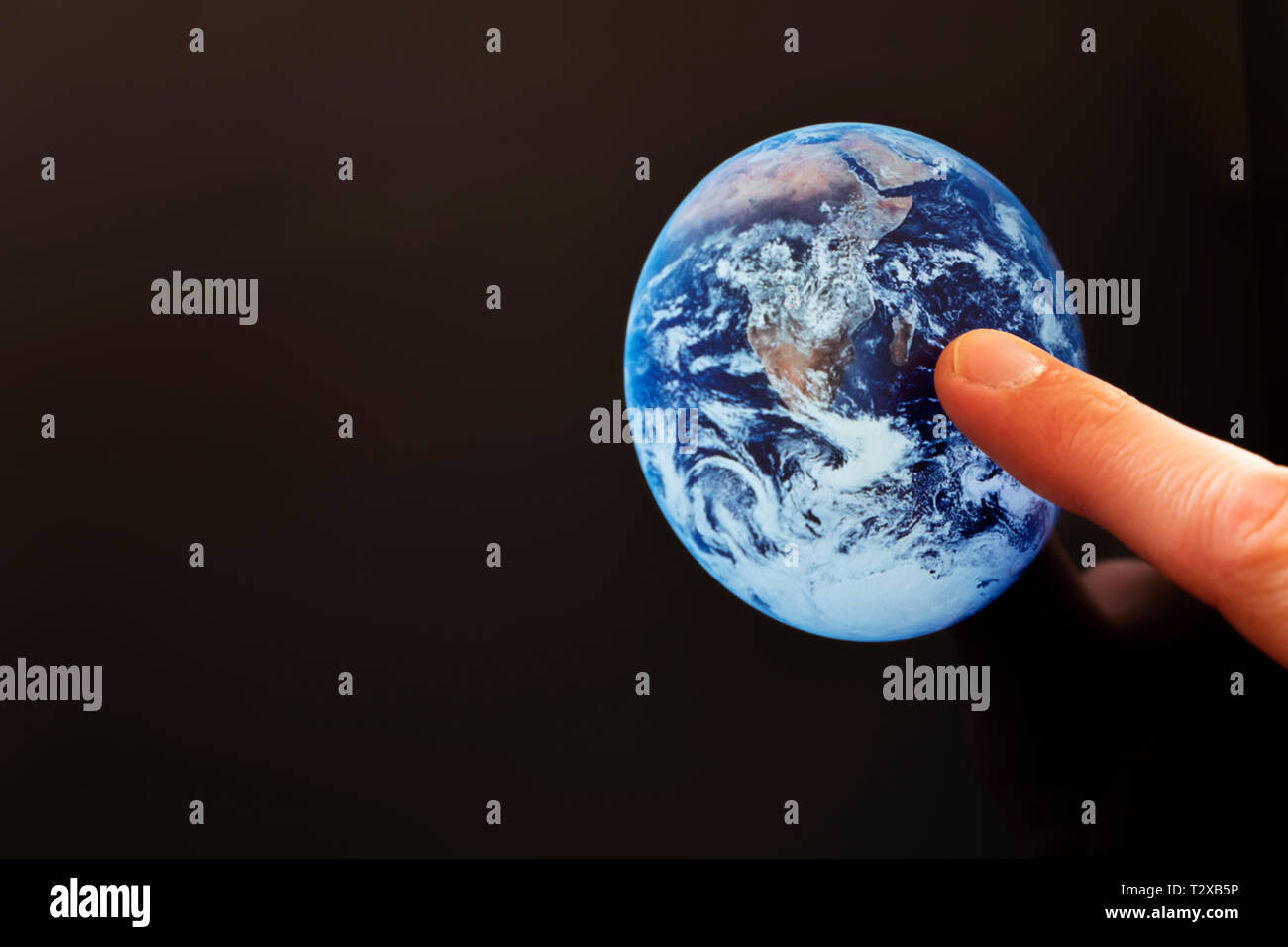 A caucasian man pointing at the earth on a screen Stock Photo