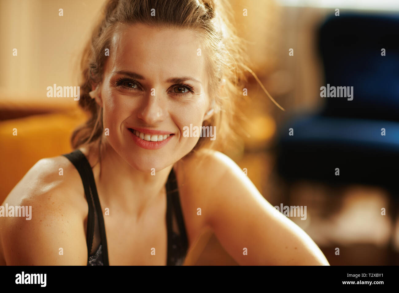 Portrait of happy young woman in sport clothes in the modern house. Stock Photo