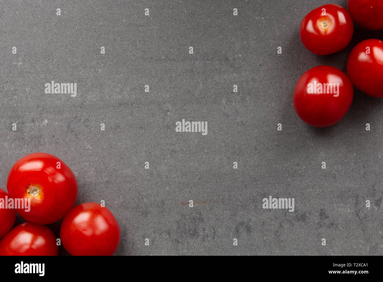 red cherry tomatoes en each corner of frame. Gray background Stock Photo