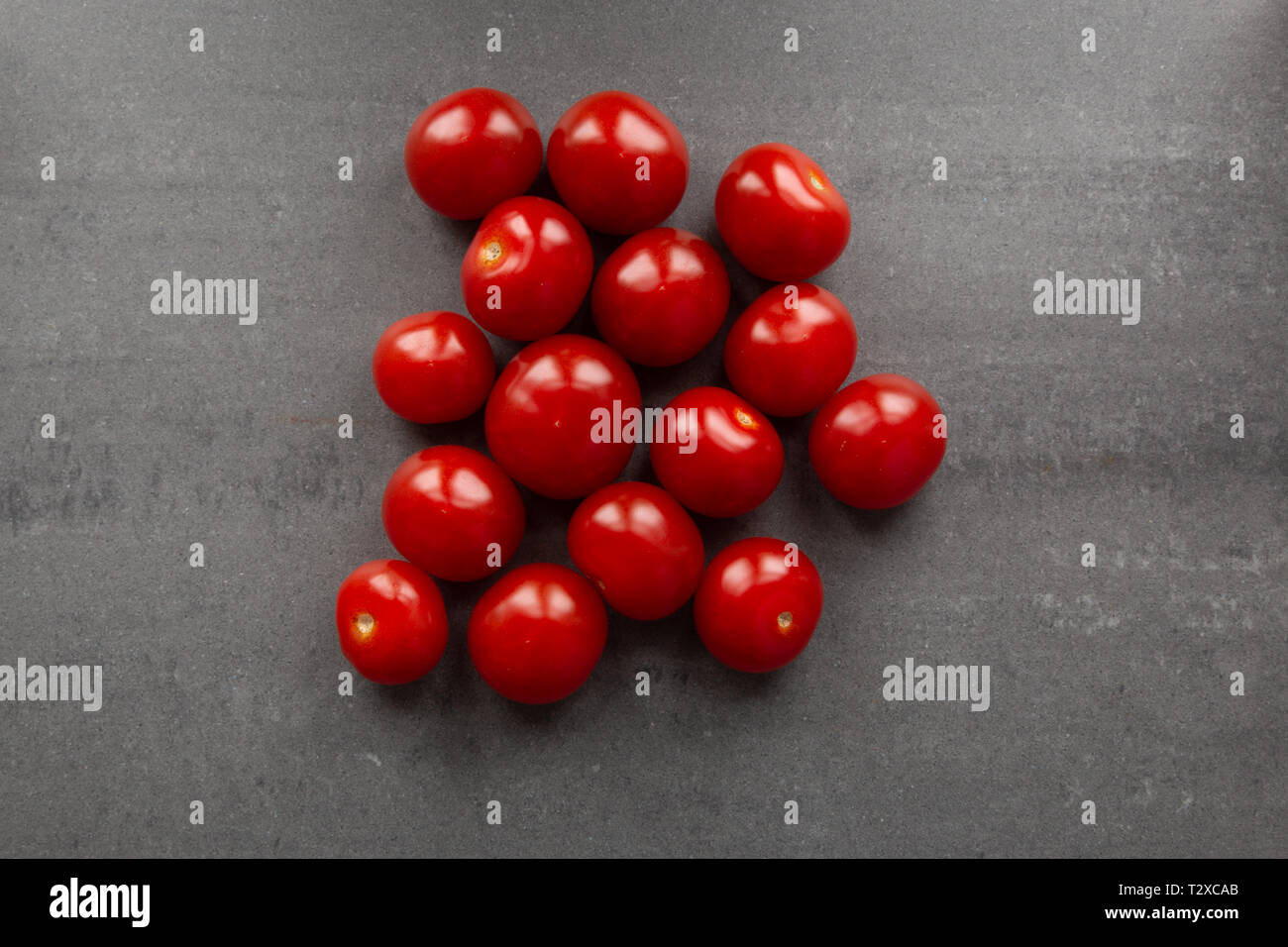 Red cherry tomatoes in center of frame. gray stone background. Stock Photo