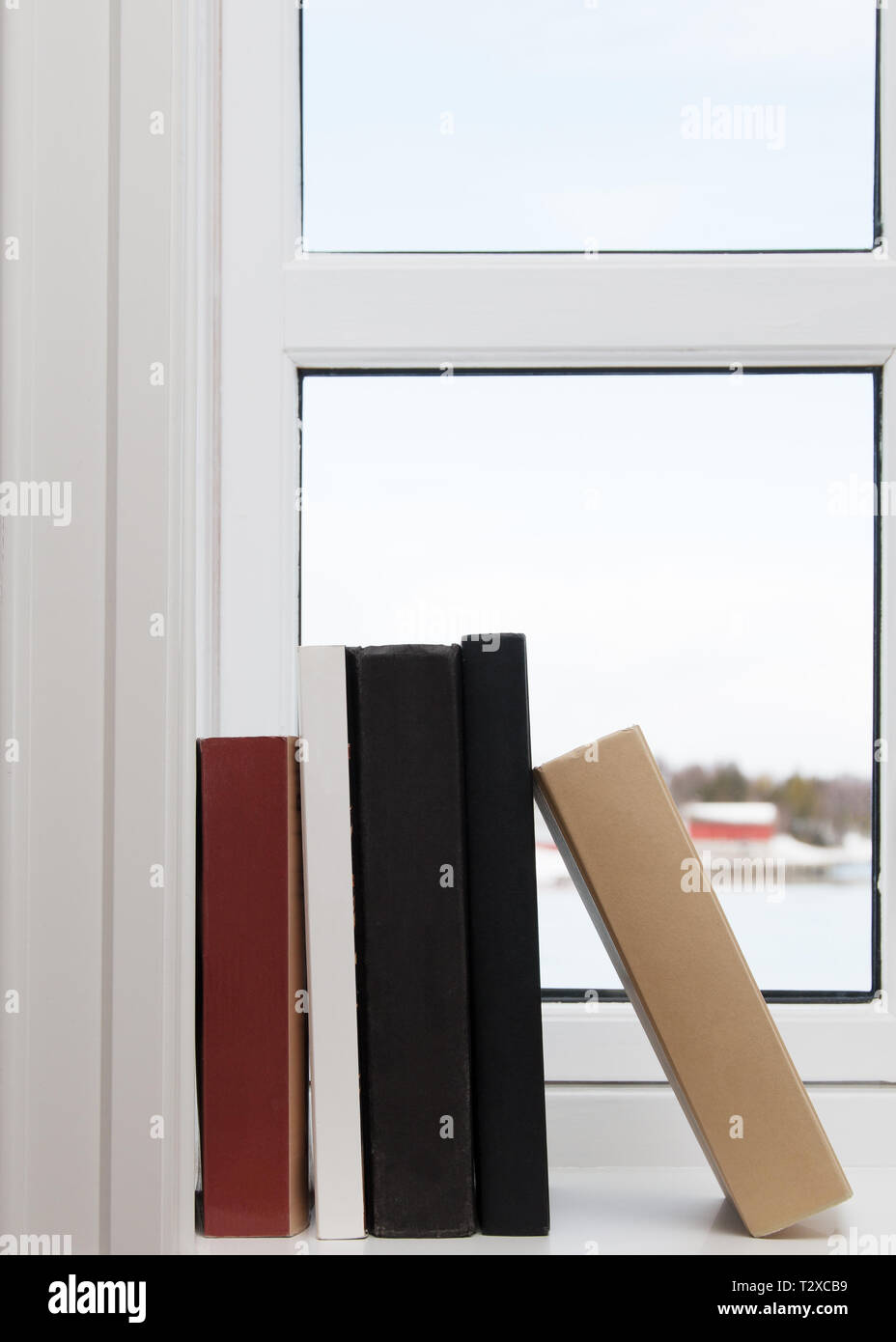Books standing in white windowsill Stock Photo