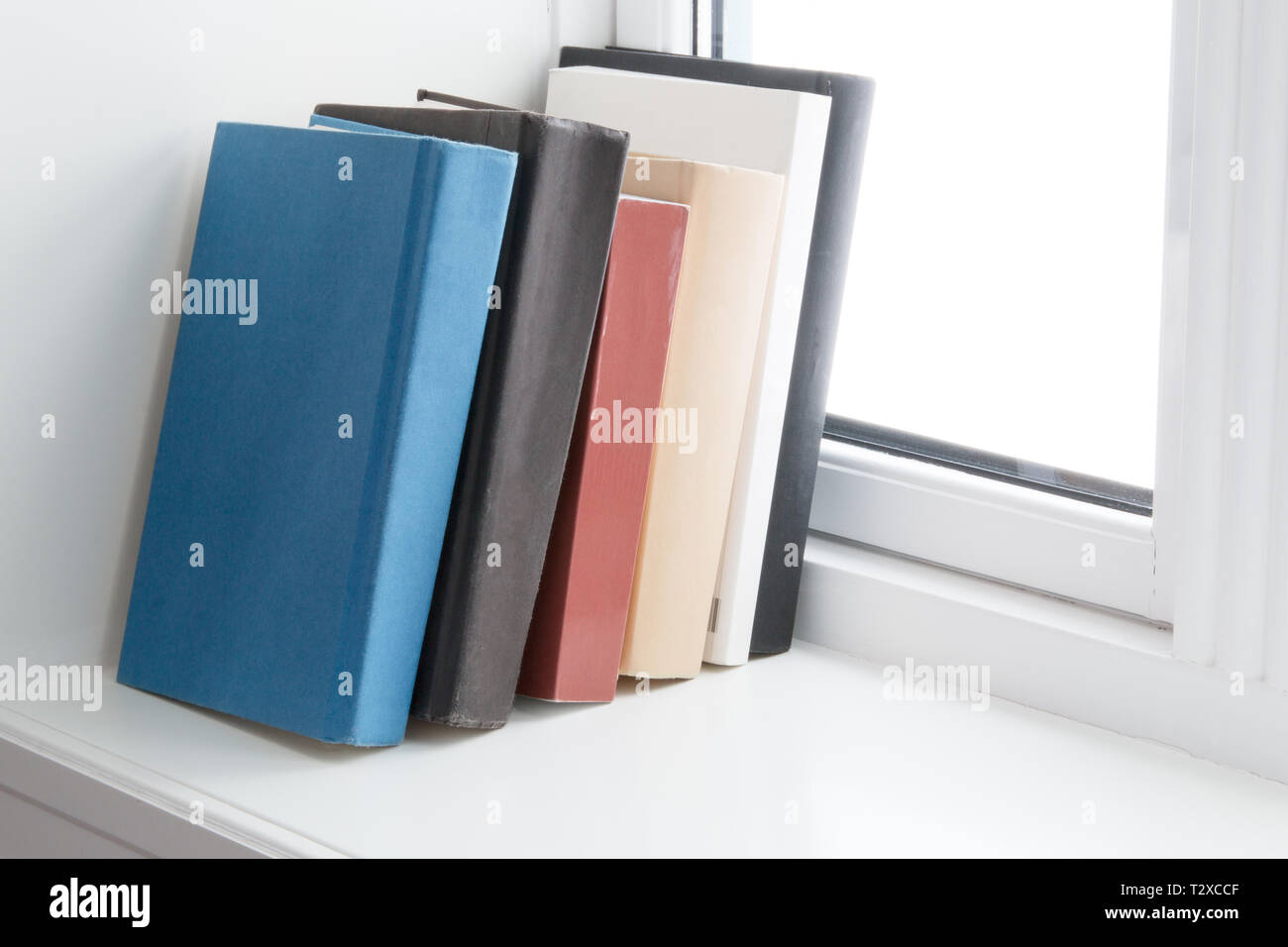 books of different colour in windowsill Stock Photo