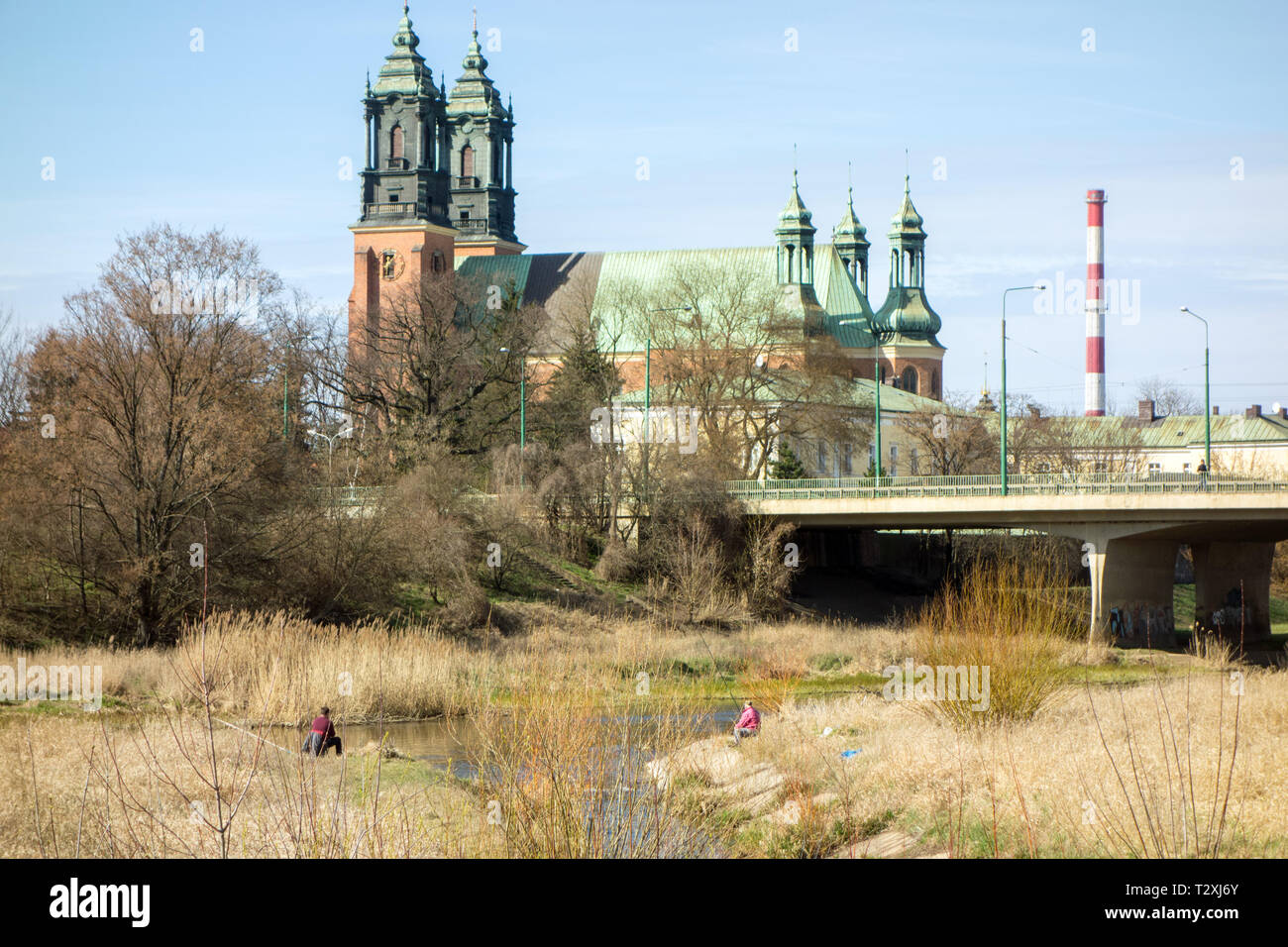 Two men fishing in a river in front of the cathedral of St Peter and St Paul on Ostrow Tumski island in the Polish city of Poznan Poland Stock Photo