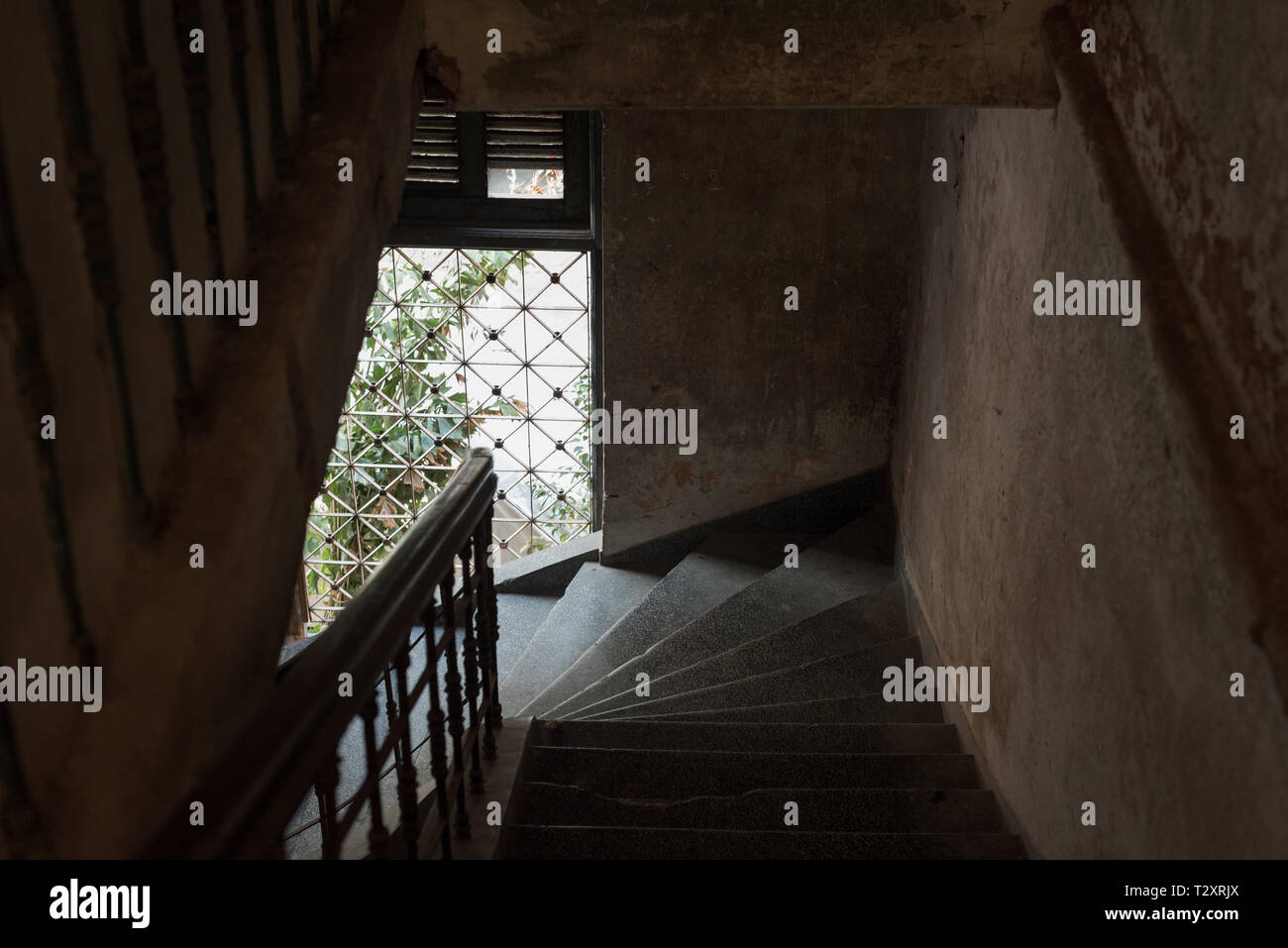 Dark stair descent in an old house with natural light coming from a barred window. The Mansion or Villa Bodega, Phnom Penh, Cambodia. Stock Photo