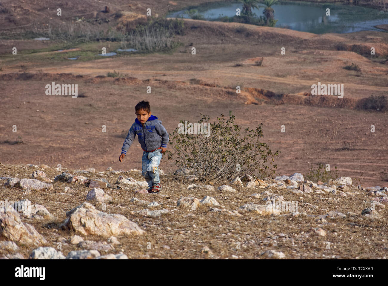 Indian kid climbing up the hill by running. Stock Photo
