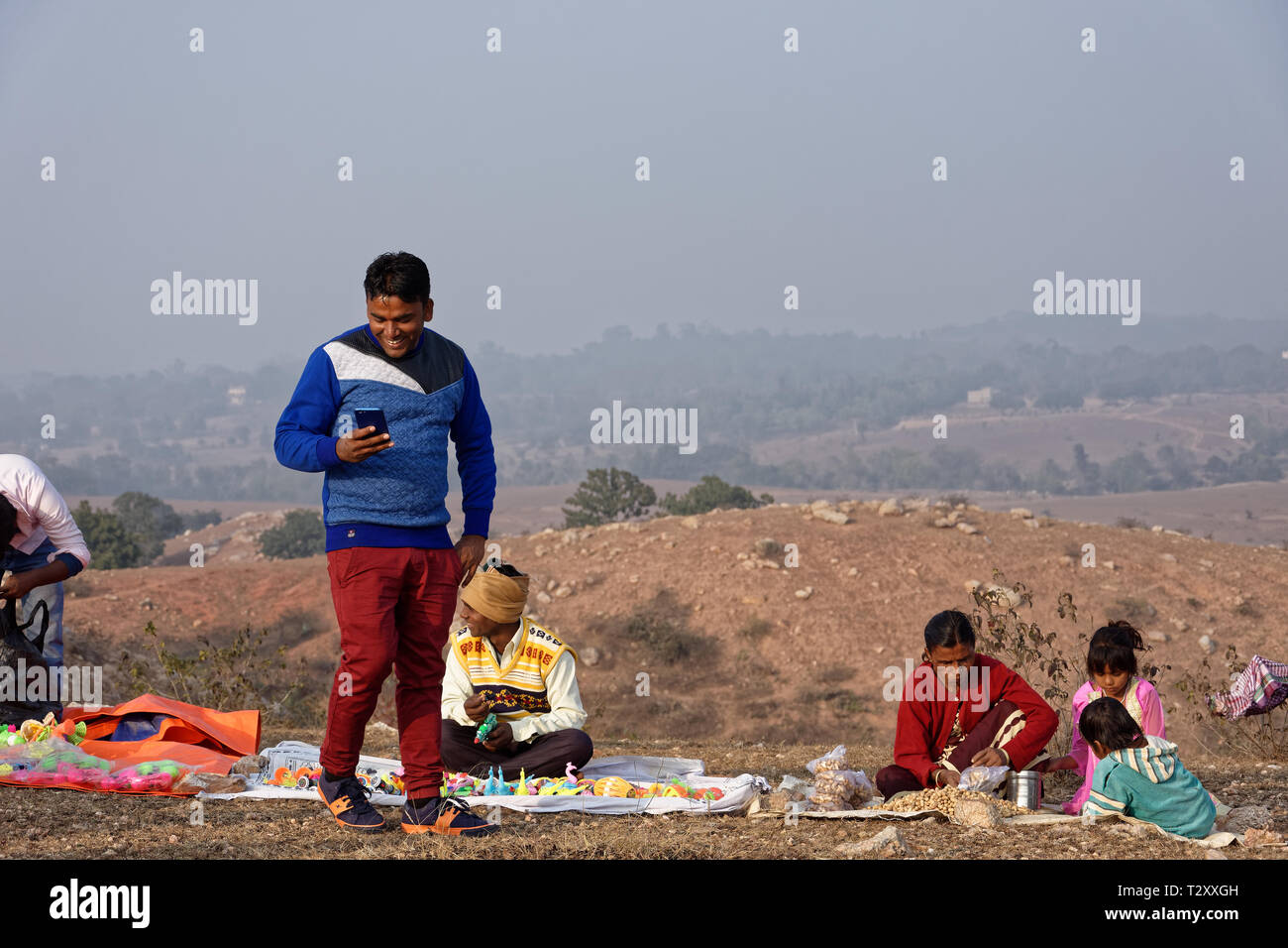 An Indian man is smiling with cellphone in a rural hilltop fair. Stock Photo