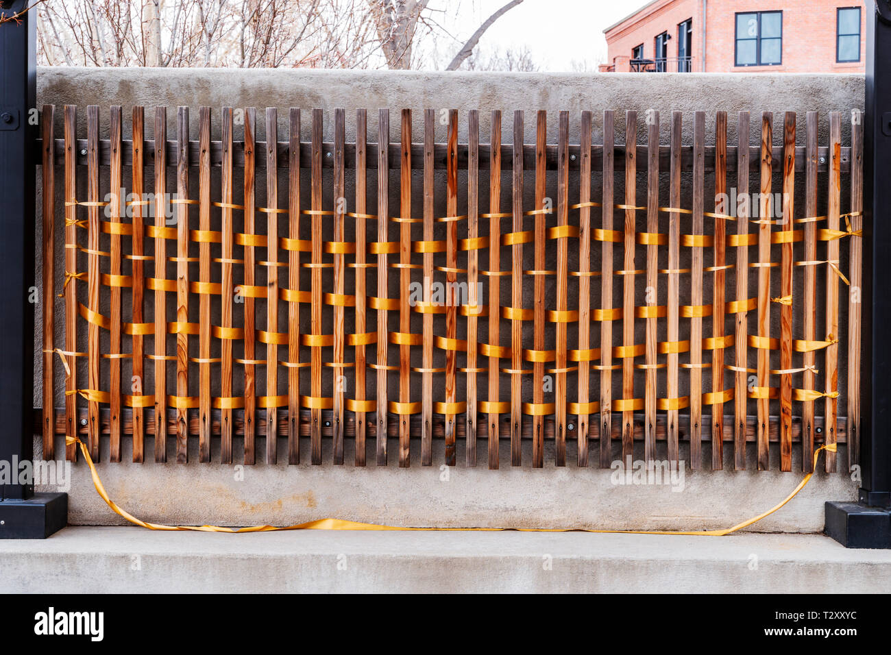 An unknown artist weaves golden ribbon through fence slats; Salida SteamPlant Event Center; Salida; Colorado; USA Stock Photo
