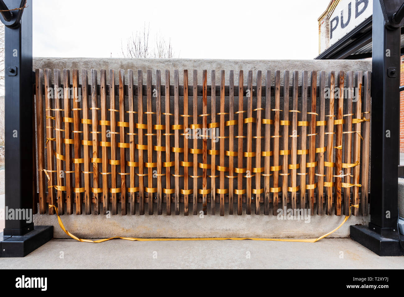 An unknown artist weaves golden ribbon through fence slats; Salida SteamPlant Event Center; Salida; Colorado; USA Stock Photo