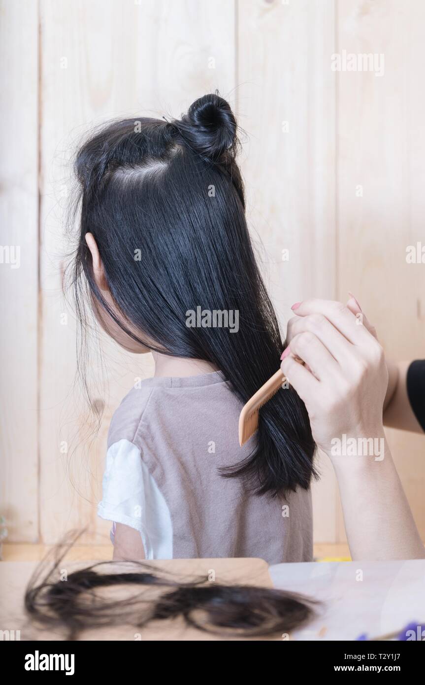 Cropped hand of mother combing daughter's hair Stock Photo