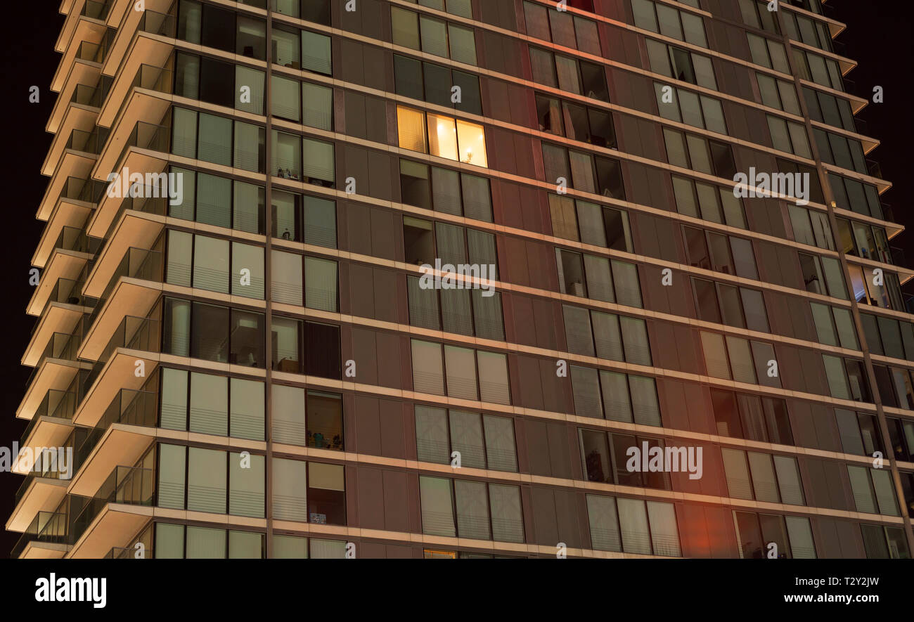 Single lit window in a modern apartment block Stock Photo