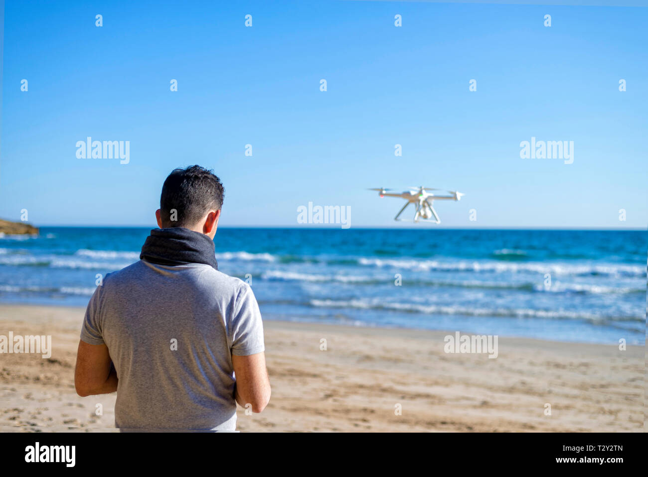 Rear view of a Man on a beach testing its drone and recording v Stock Photo