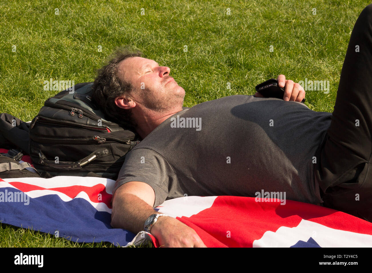 Man lying on the grass on a British flag Stock Photo