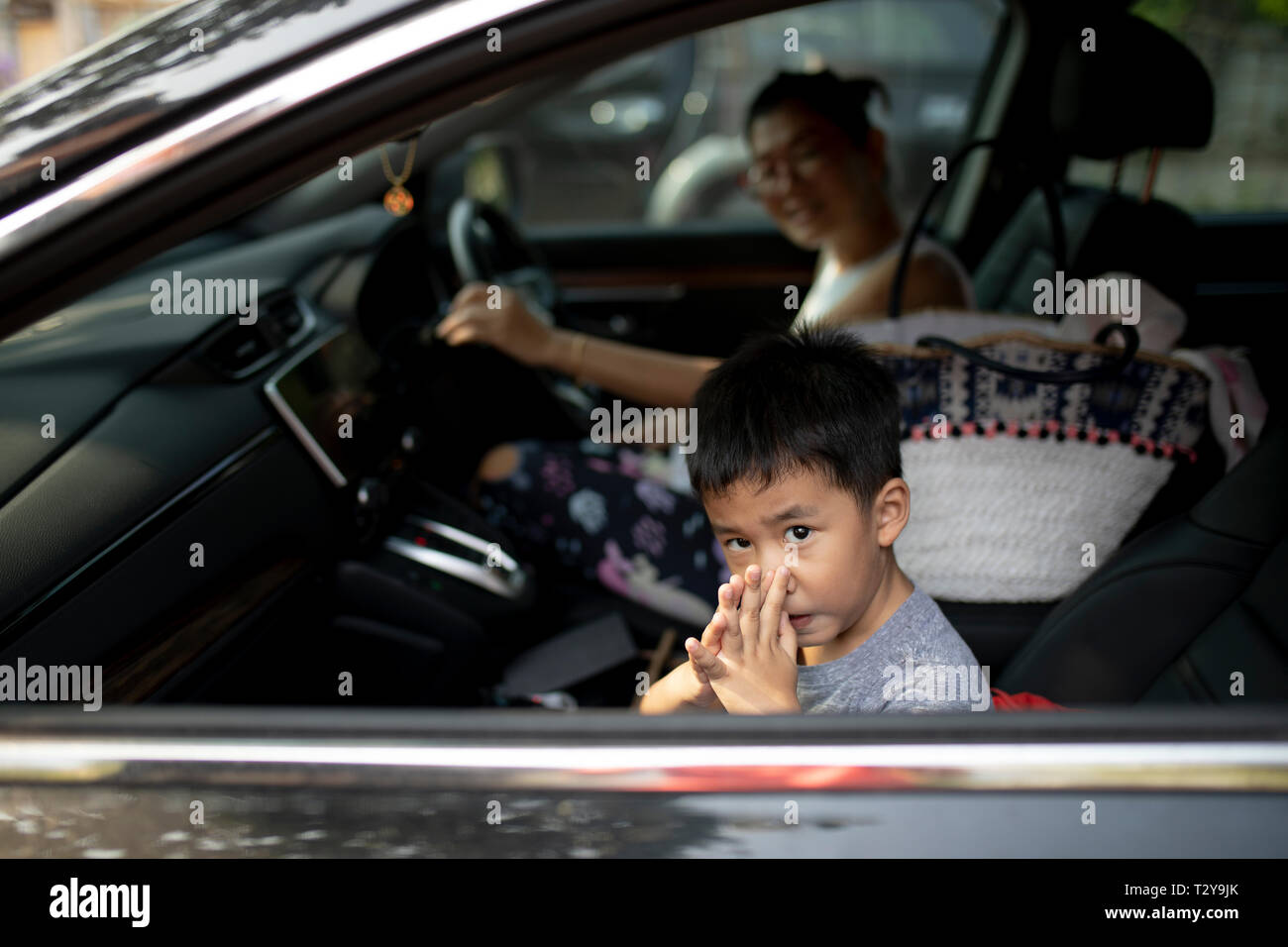 asian children sitting on passenger seat and go to school with mother