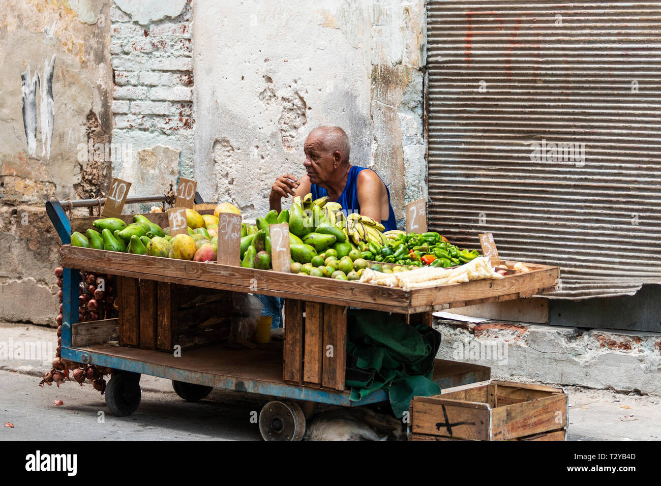 Havana, Cuba - 25 July 2018: A man sitting behind his fruit cart smoking a cigarette while selling fruit on the streets of Havana Cuba. Stock Photo