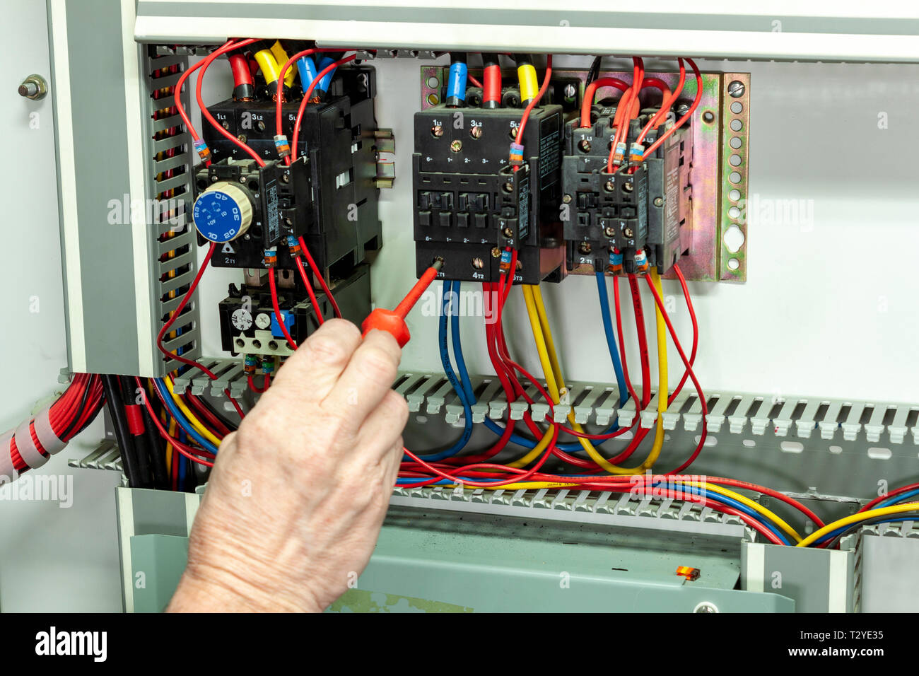 Electricial engineer tightening connections on a contactor in a control