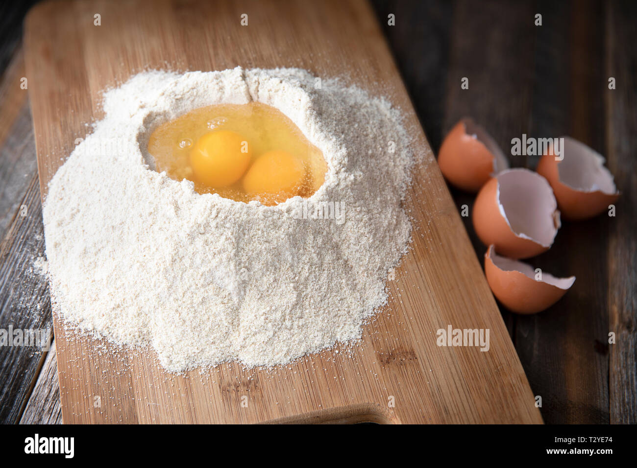 Two eggs in flour with egg shells on the side. Stock Photo
