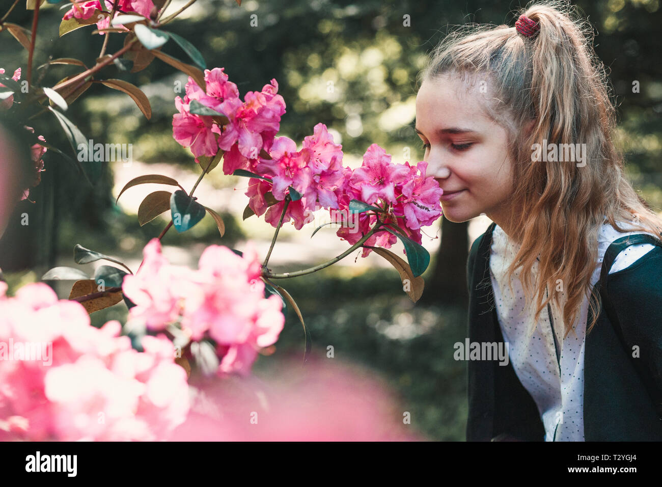 Girl with closed eyes standing in garden among the flowers, smelling ...