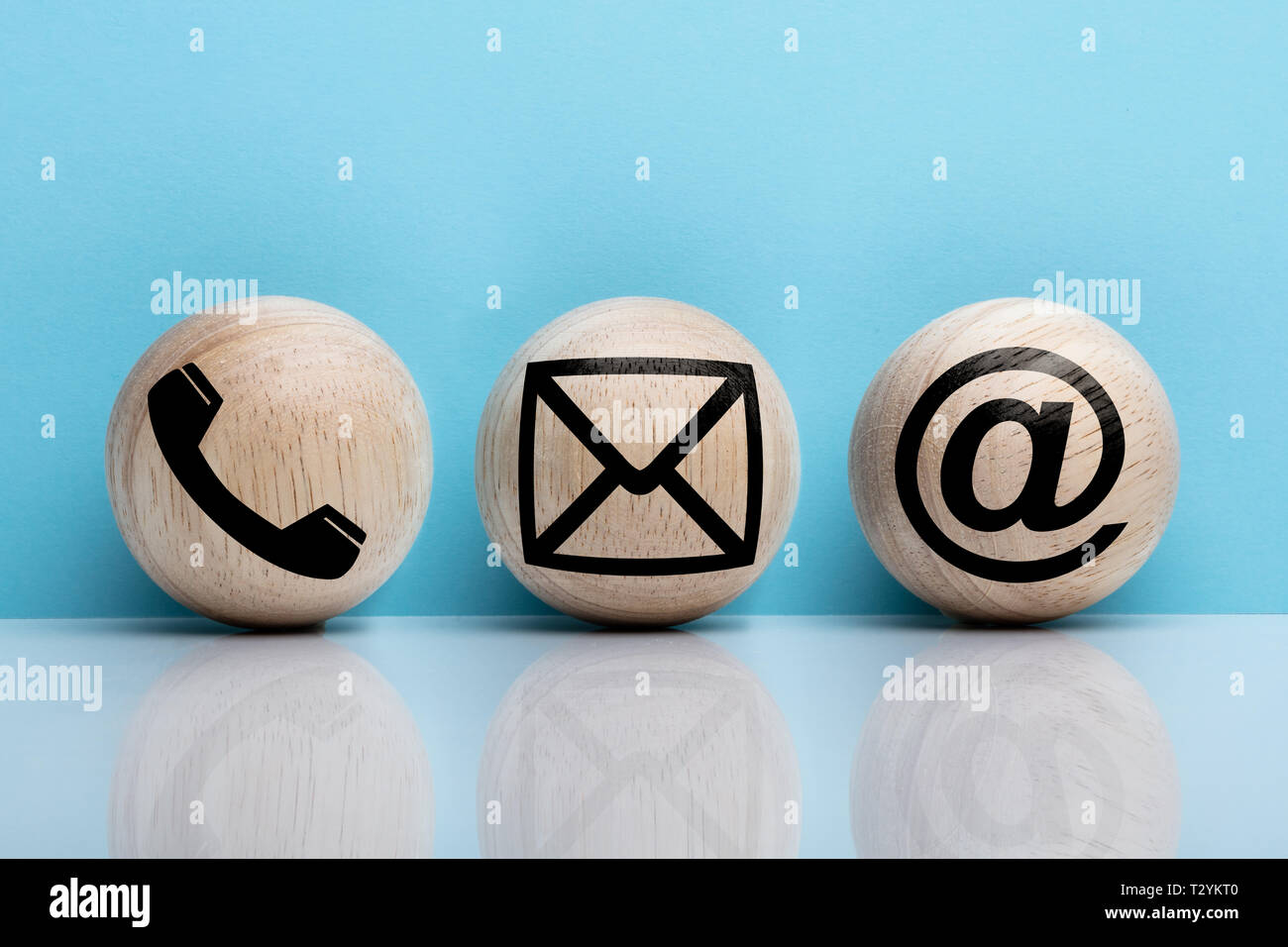Three Wooden Ball With Contact Icon Arranging In A Row Over Reflecting Floor Stock Photo