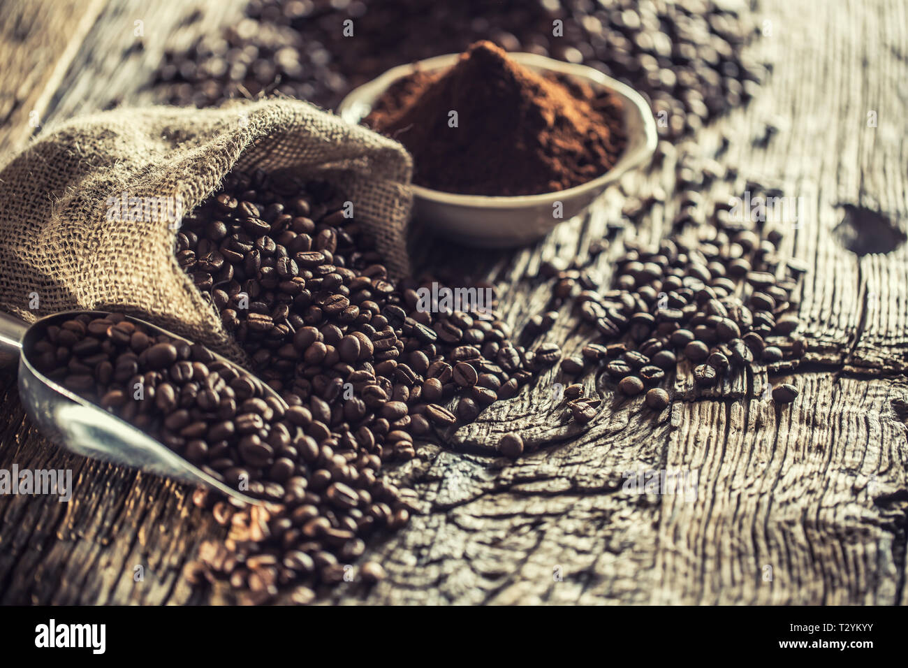 Coffee beans in burlap sack on old wooden table. Stock Photo