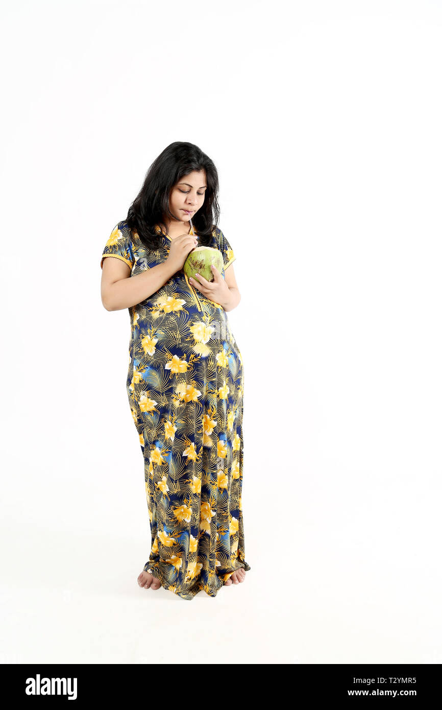 Young pregnant lady is drinking coconut water. Isolated on the white