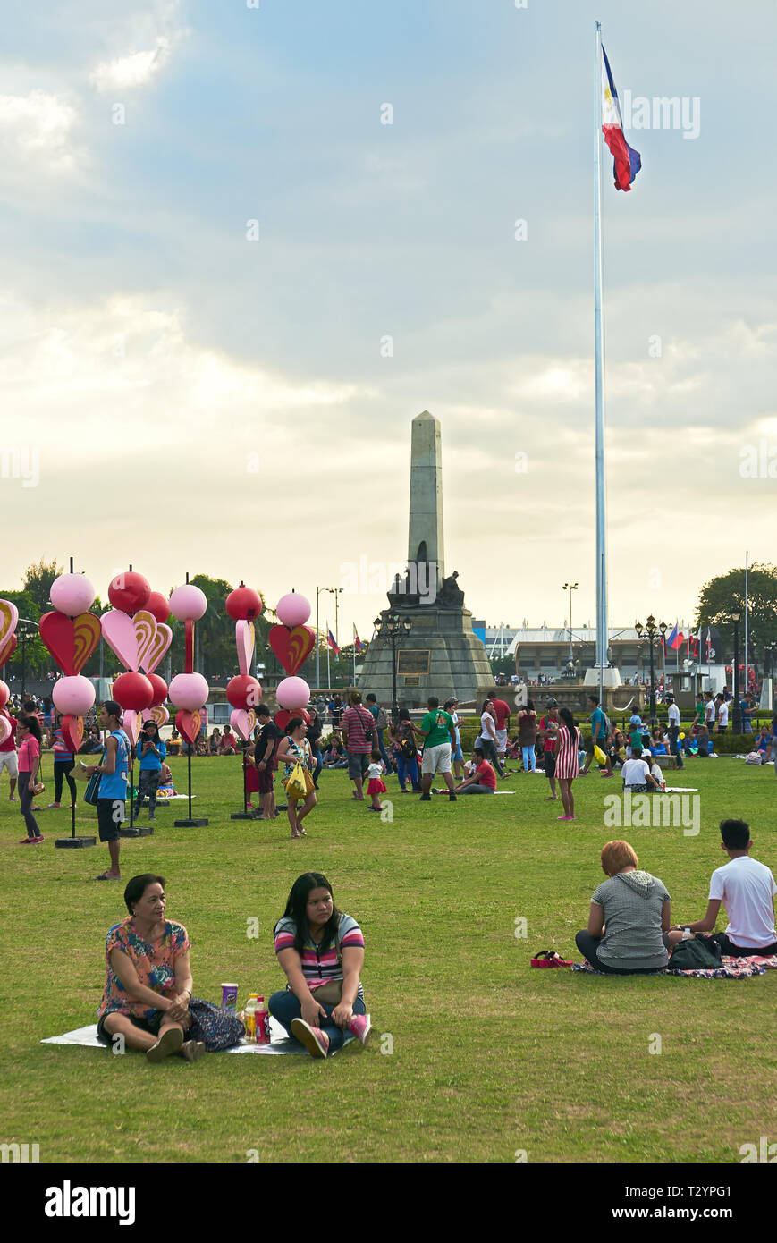 Manila, Philippines: Festive scene with people at the Luneta Park with the Rizal Monument and Philippine flag in the background Stock Photo