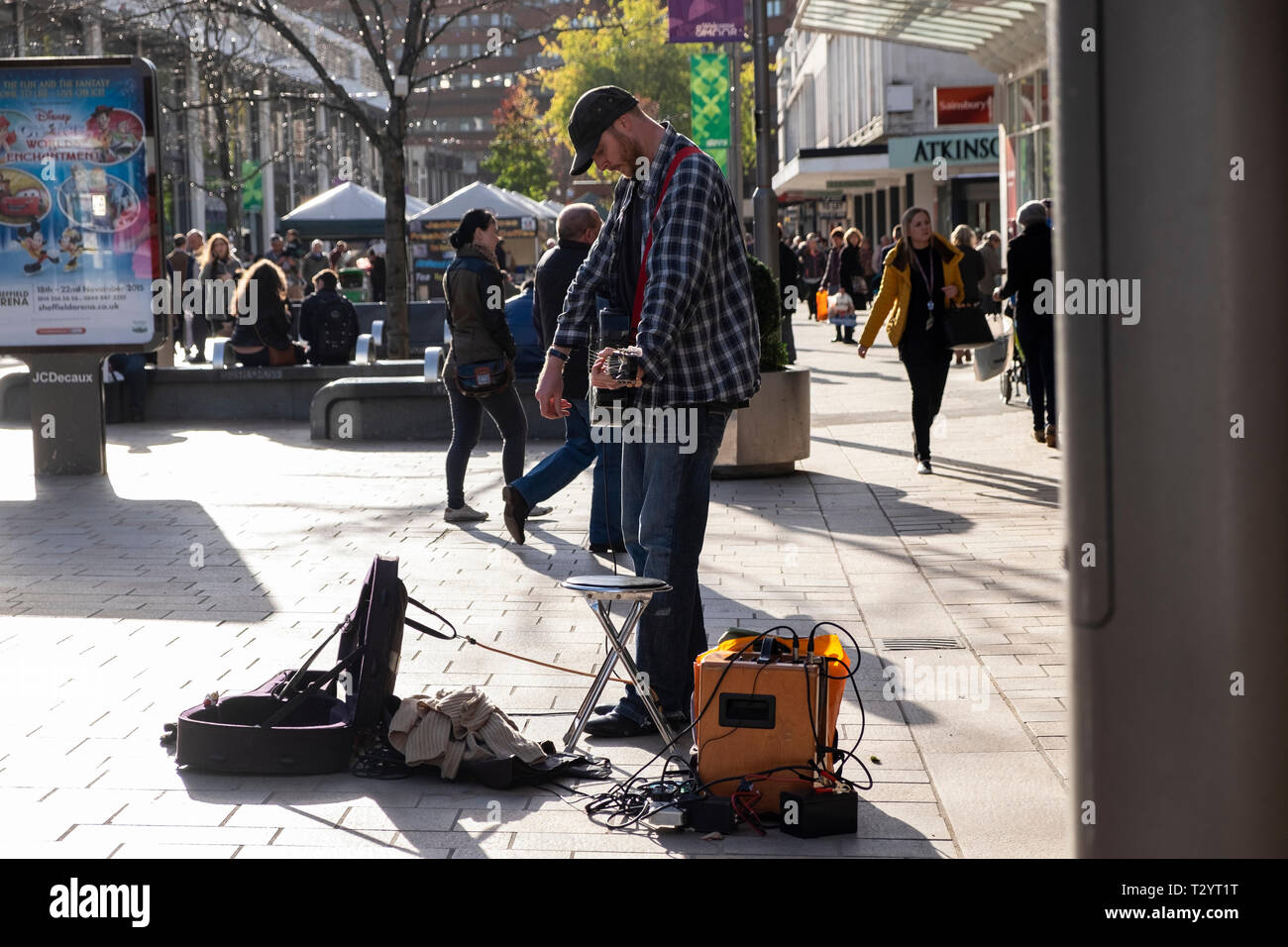 Busker with acoustic guitar and amplifier palying on the Moor pedestrian shopping precinct on a Winter's day in Sheffield Stock Photo