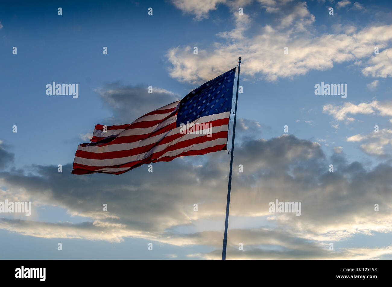 The Flag of the United States of America flying on a pole in a cloudy ...