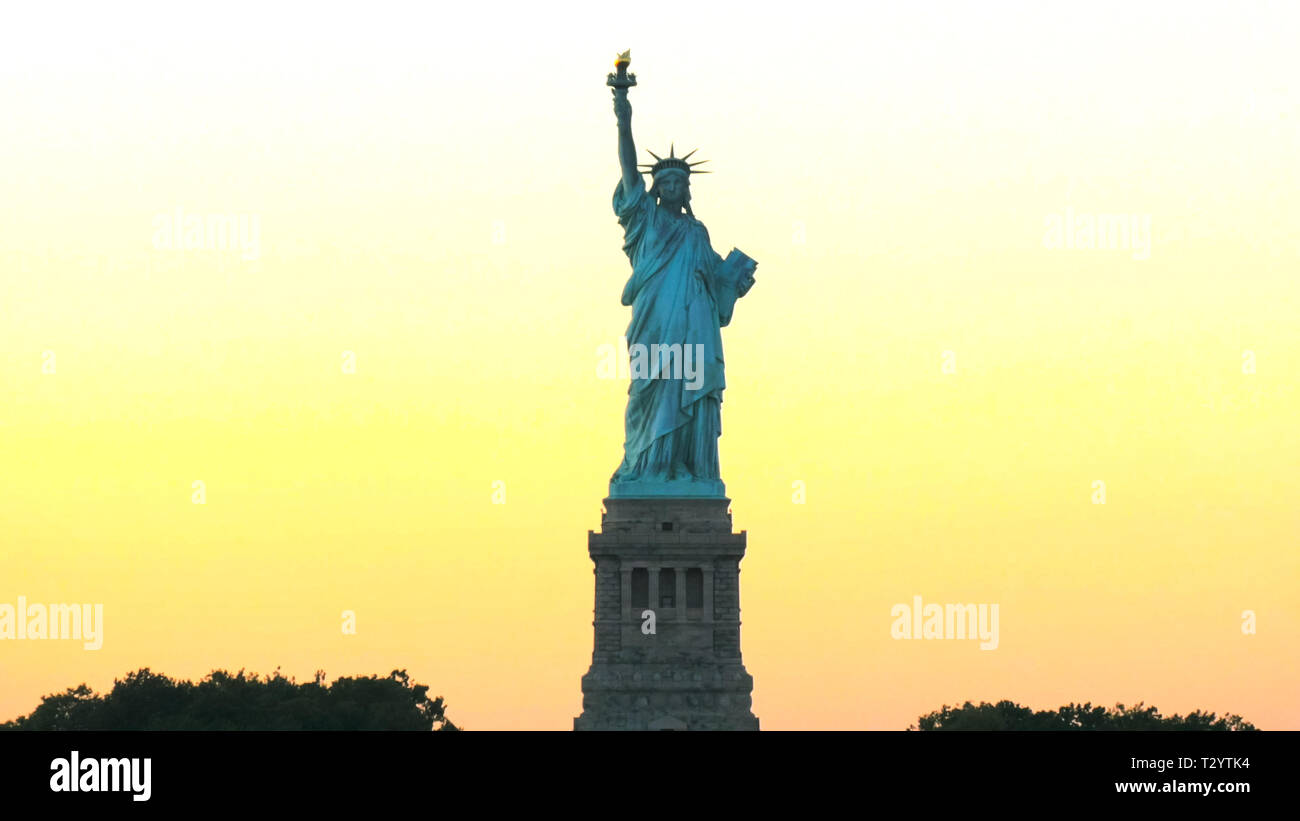 golden sunset and a silhouetted statue of liberty in new york Stock ...