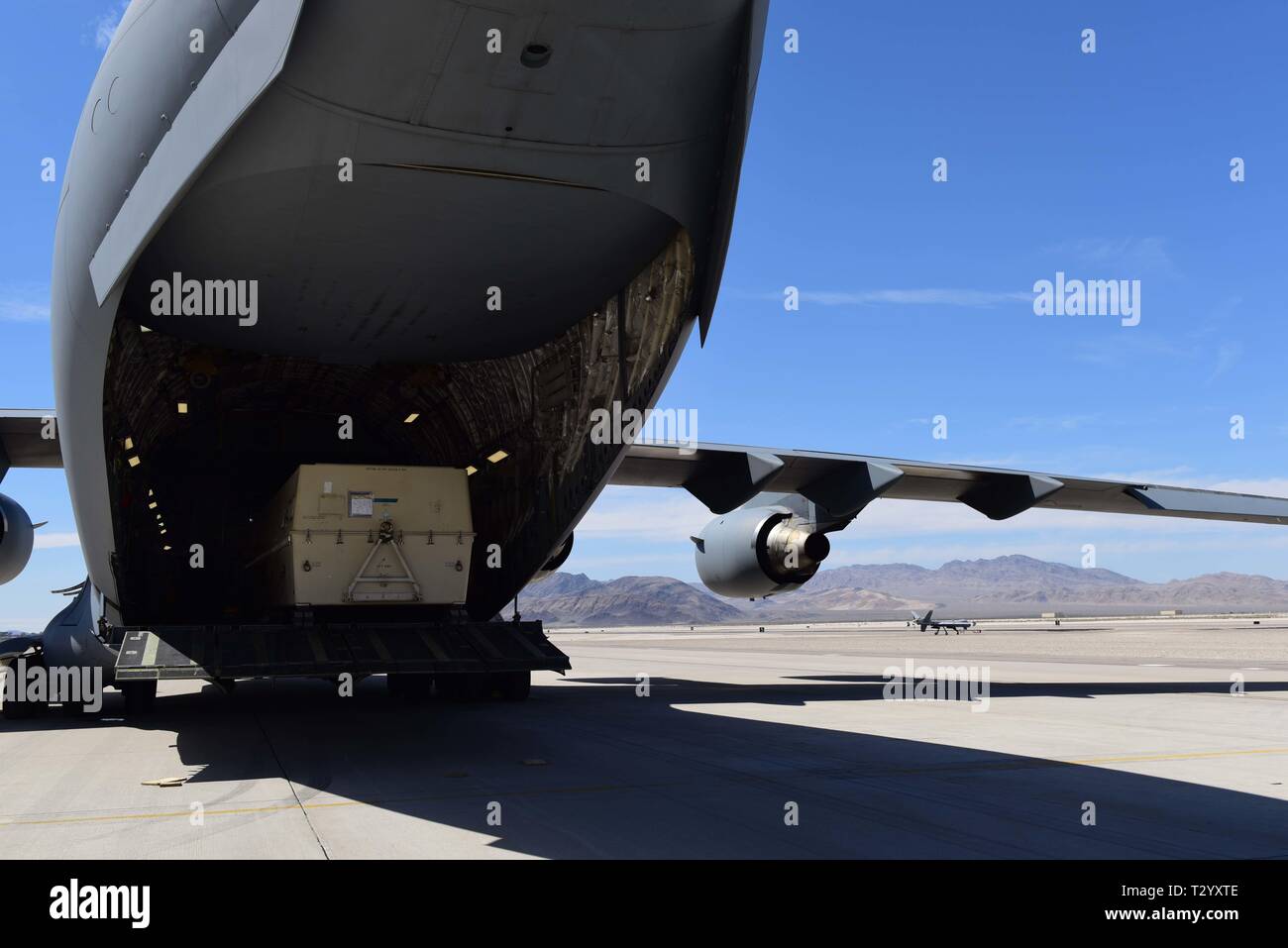 An MQ-9 Reaper Remotely Piloted Aircraft gets loaded onto a C-17 Globemaster III at Creech Air Force Base, Nevada, Mar. 27, 2019. Reapers are broken down and packed into boxes, then flown on cargo aircraft like the C-17 to various areas of responsibility around the world. (U.S. Air Force photo by Airman 1st Class Haley Stevens) Stock Photo