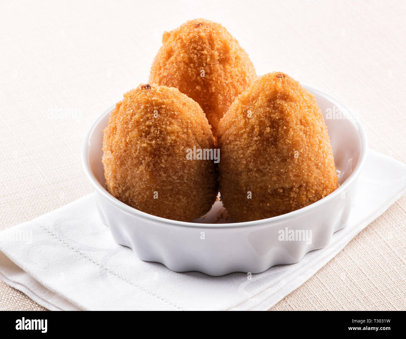 Three deep fried Arancini, breaded rice balls with a savory stuffing, from Sicily served in a