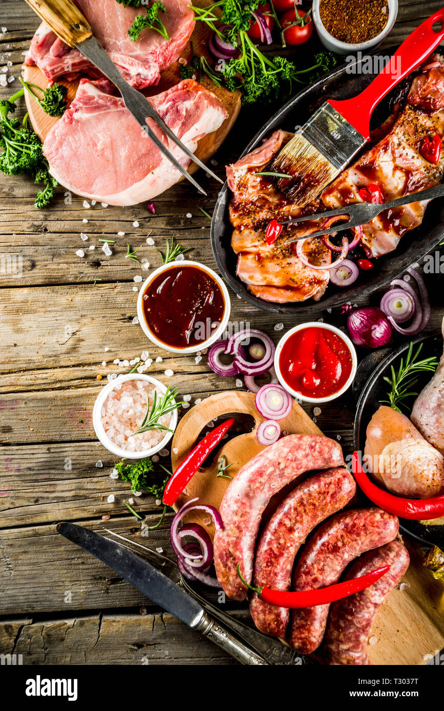 Various raw meat ready for grill and bbq, with vegetables, greens, sauces  kitchen grilling utensils. Chicken legs, pork steaks, sausages, beef ribs  wi Stock Photo - Alamy