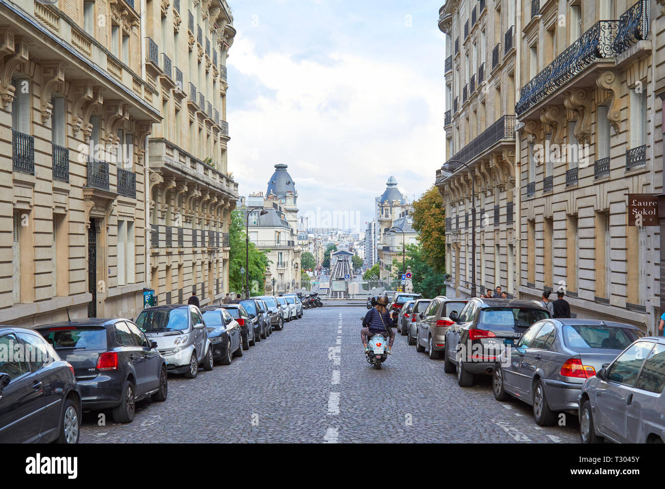 PARIS, FRANCE - JULY 22, 2017: Street in Paris with perspective, man and woman riding moped in France Stock Photo