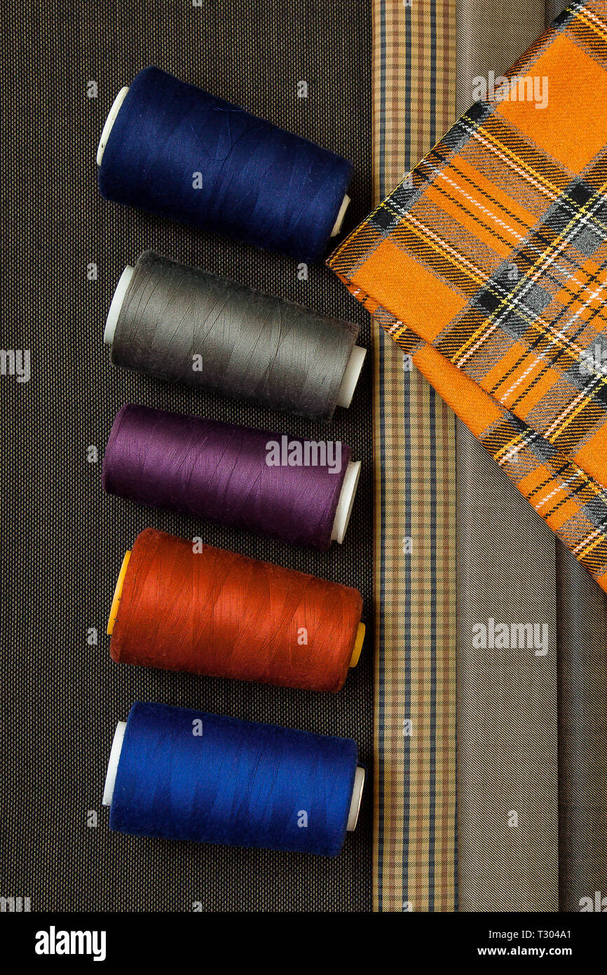 Many different in color threads lie on the sewing table along with the ...