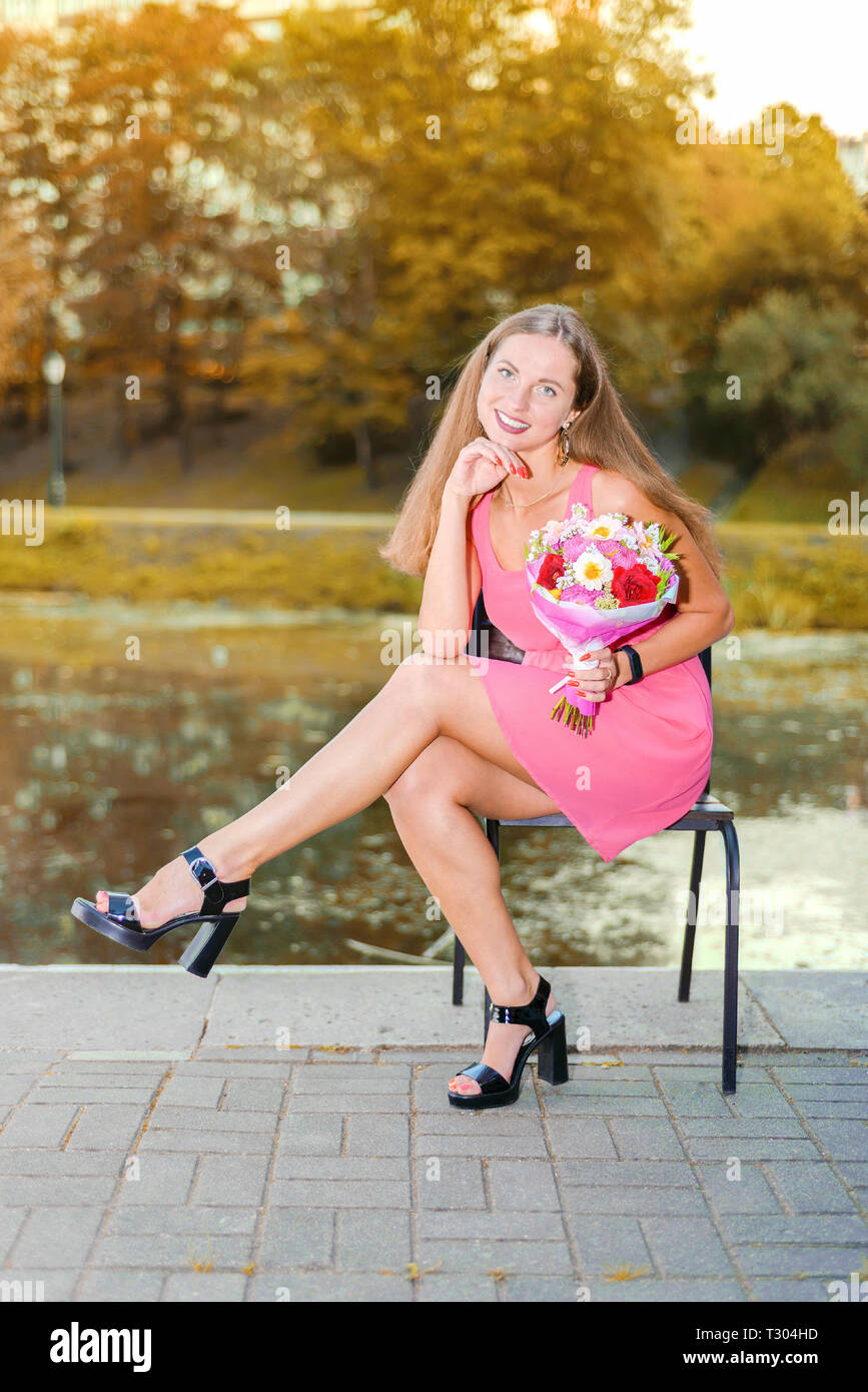 beautiful happy girl in pink dress with flowers and balls sitting on ...