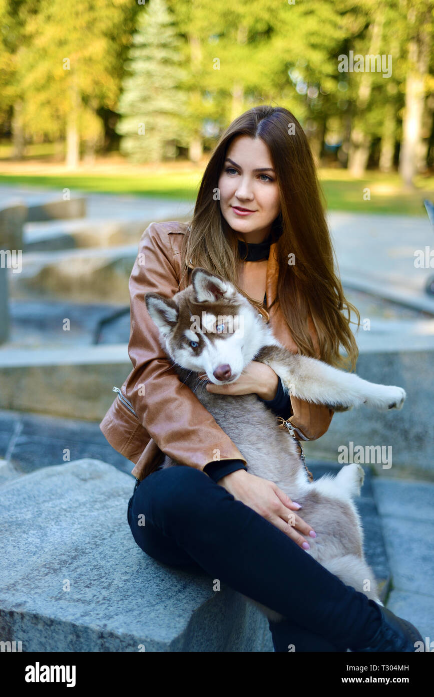 beautiful girl holding dog. husky puppy funny looks away Stock Photo - Alamy