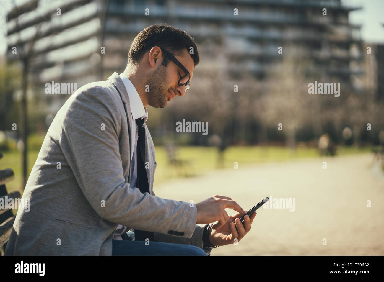 Young businessman is using smartphone in park. Stock Photo