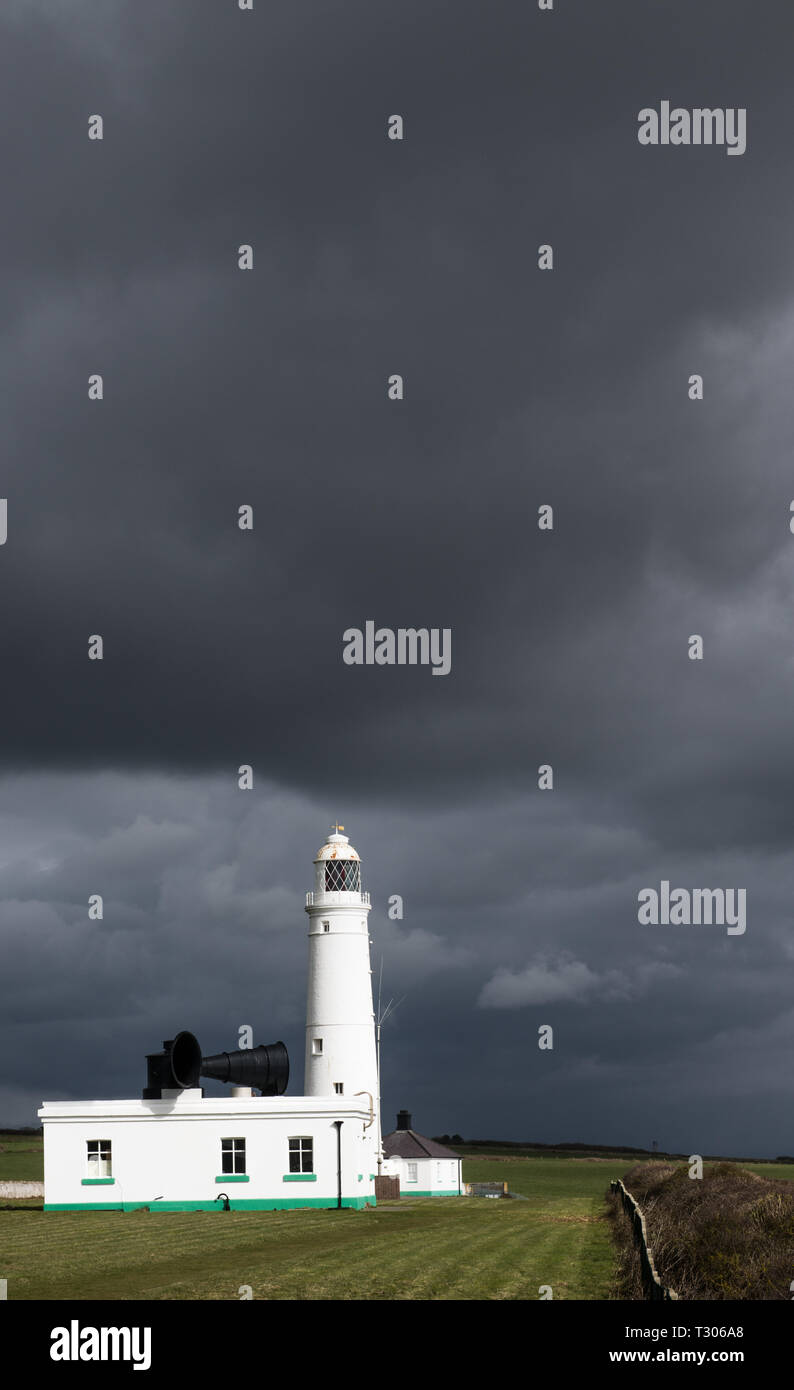 The Nash Point Lighthouse looking out over Bristol Channel against a dark sky on the Glamorgan Heritage Coast south Wales in a portrait format. Stock Photo