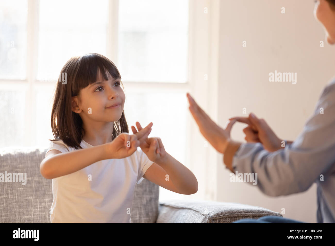Mother daughter sitting on couch nonverbal communicating with sign language Stock Photo