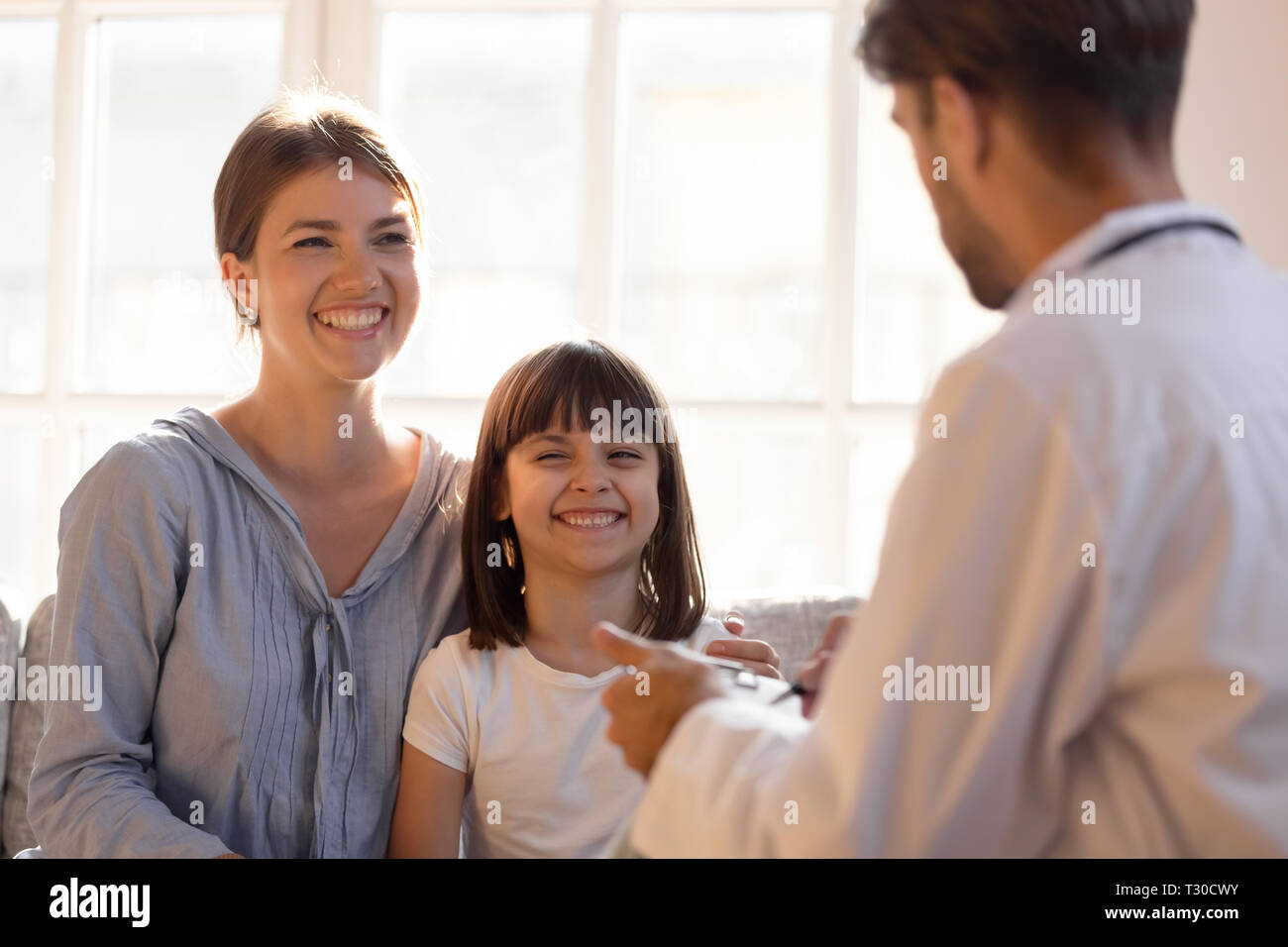 Paediatrician male doctor writing patient information focus on little girl Stock Photo